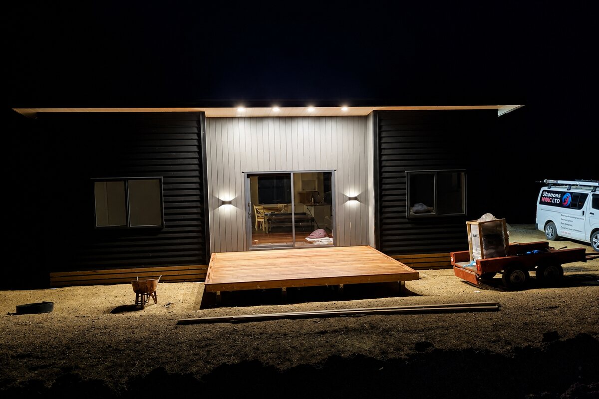 A new build at night with the exterior lighting on and a Shannons HVAC van parked alongside